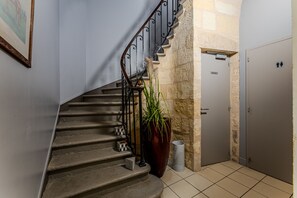 Eine Treppe mit Metallgeländer, ein Blumentopf, ein Mülleimer und eine Tür mit einem Schild.