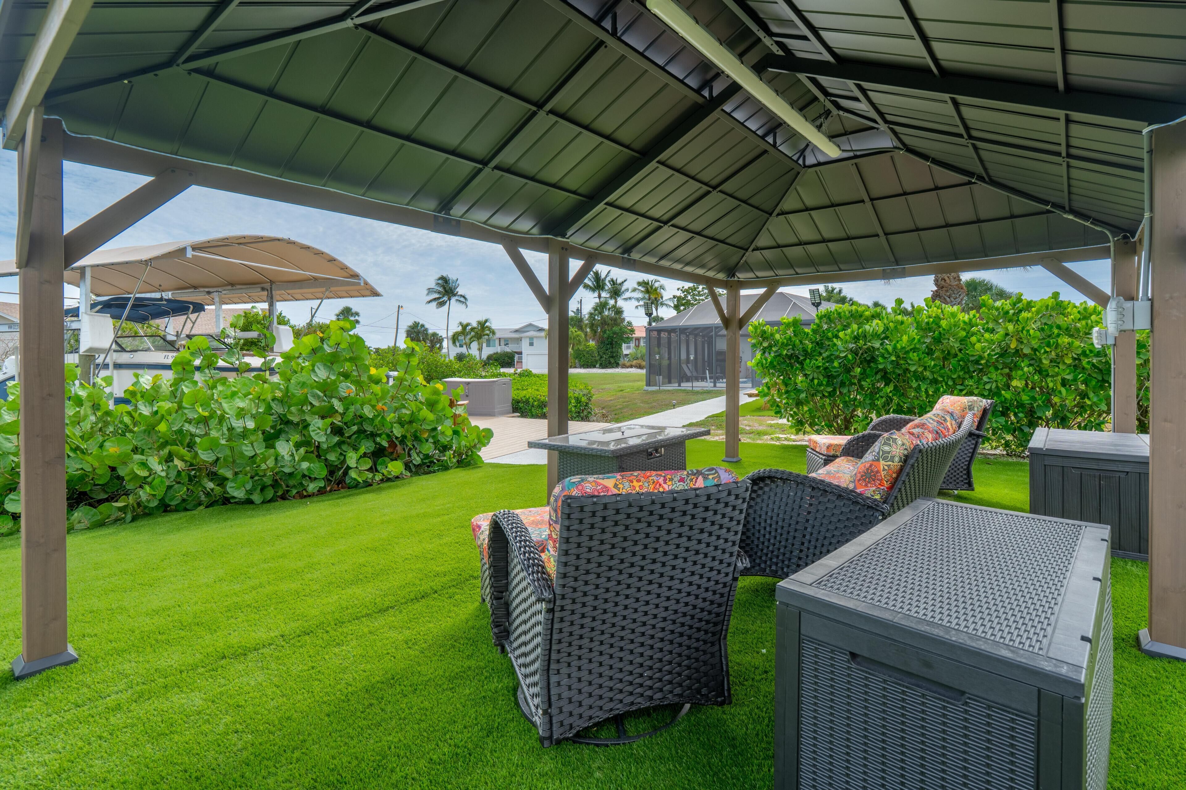 Eine überdachte Terrasse mit Korbmöbeln und Grillplatz.
