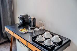 Eine Küchenzeile mit einer Kaffeemaschine, einem Wasserkocher und Weingläsern auf einer schwarzen Arbeitsplatte.