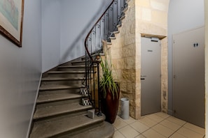 Eine Treppe mit Metallgeländer, ein Blumentopf, ein Mülleimer und eine Tür mit einem Schild.