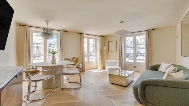 Un salon moderne avec un coin repas, de grandes fenêtres et un canapé vert.