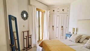 Un dormitorio con una cama, un armario, un espejo y una ventana con cortinas.