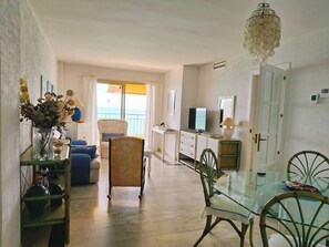 Een ruime woonkamer met balkon, eettafel en televisie.