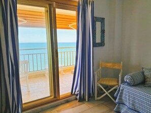A room with a view of the sea, a wooden ceiling, a white chair, and a bed with blue bedding. - Apartment in front of the sea with beautiful views. The beach just below (Fuengirola)