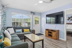 Una sala de estar con un sofá modular, una mesa de centro, un televisor y un mueble de madera para entretenimiento.