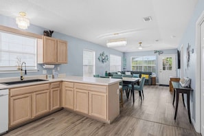 Una cocina moderna con armarios de madera, una isla central y un comedor con mesa y sillas.