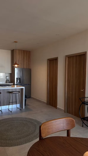 A modern kitchen with a built-in refrigerator, a coffee machine, and a dining area with a wooden table and chairs. - Tropical luxury (Puerto Vallarta)
