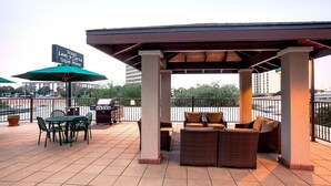 An outdoor patio area with a covered seating area, a table with chairs, and a sign for Texas Land & Cattle Steak House. - Accessible 1BR Suite | Hot Breakfast & Pool Access (San Antonio)