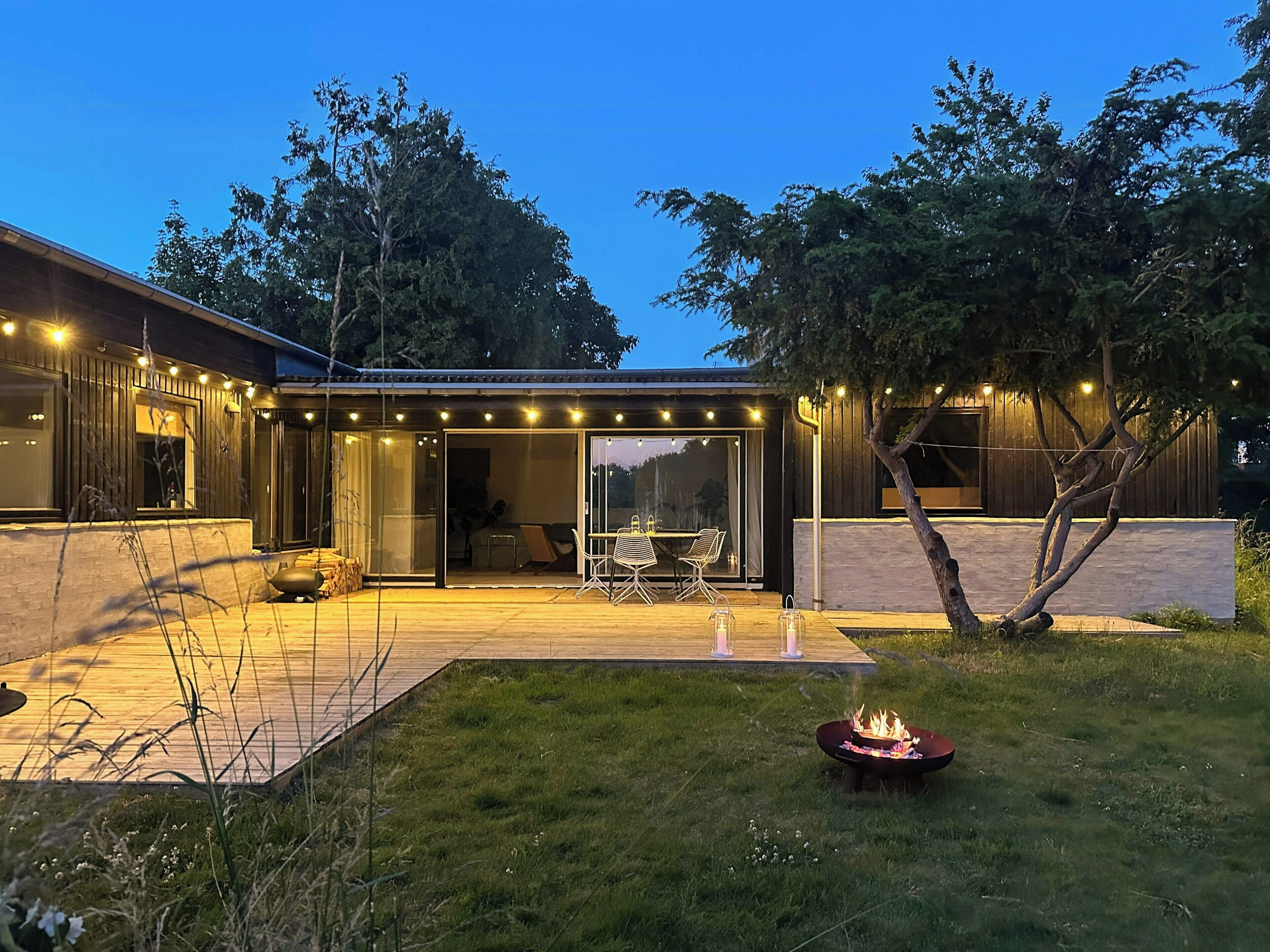 A modern house with a patio, outdoor seating, and a fire pit.