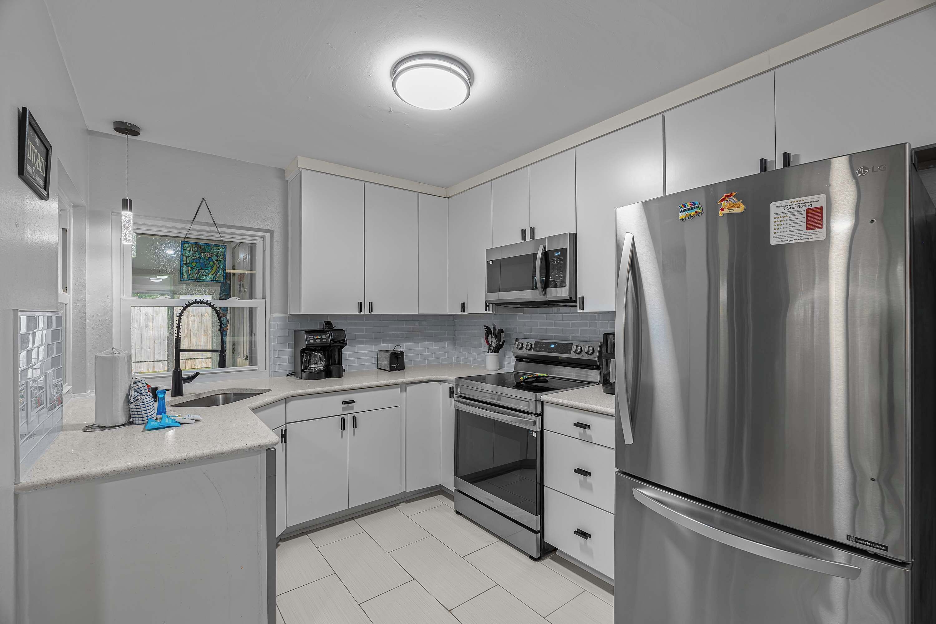 Una cucina moderna con elettrodomestici in acciaio inossidabile, mobili bianchi e una finestra vista panoramica.