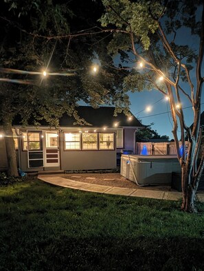 Una casa con un porche techado, un jacuzzi y luces colgantes.