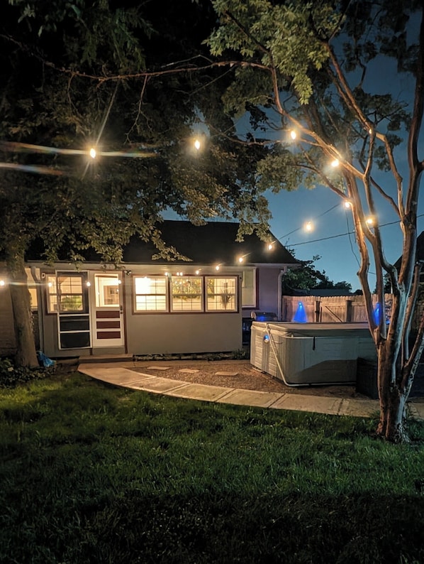 A house with a covered patio, a hot tub, and string lights.