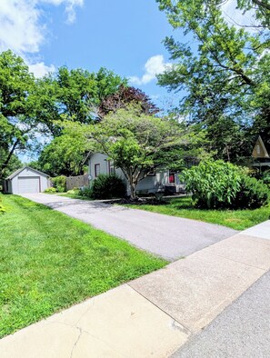 A residential street with houses, a driveway, and a lawn.