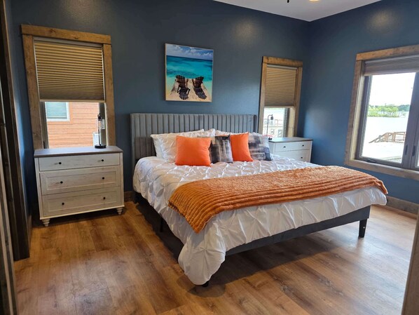 A bedroom with a bed, two nightstands, a painting, and a window.