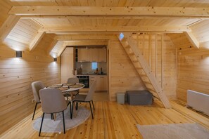 A wooden interior with a dining area, kitchen, and a staircase.