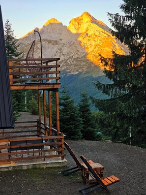 Une terrasse en bois avec une chaise et une table, offrant une vue sur un paysage montagneux.