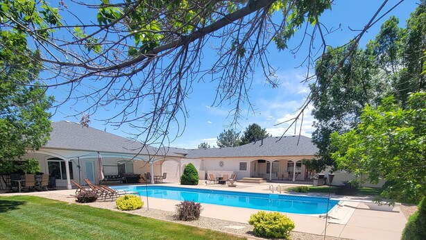 Una propiedad residencial con piscina, mobiliario de patio y zona de estar exterior cubierta.