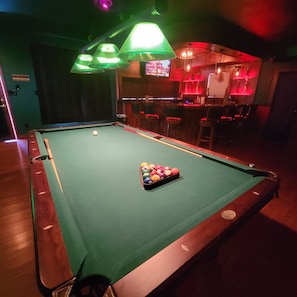 A pool table with balls, a bar area with stools, and a television screen. - Beautiful 4,000 sq ft home at the base of the Colorado National Monument. (Grand Junction)