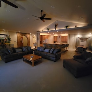 A spacious living room with a ceiling fan, a kitchen area with wooden cabinets, and a dining area with a table and chairs. - Beautiful 4,000 sq ft home at the base of the Colorado National Monument. (Grand Junction)