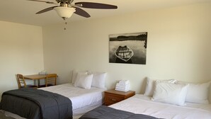 A hotel room with two beds, a desk, a chair, a nightstand, and a ceiling fan. - Sunrise 5 Studio 2 Queens (Huntsville)