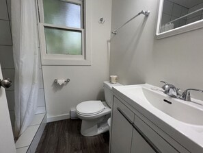 A bathroom with a toilet, sink, and window.