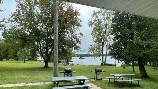 A picnic area with tables and grills by a lake. - Sunrise 5 Studio 2 Queens (Huntsville)