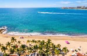 A beach with palm trees, a sandy shore, and a clear blue sea. - Icon Vallarta · 1BR Chic with Pool (Puerto Vallarta)