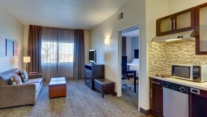 Ein Hotelzimmer mit Wohnbereich, einer Küchenzeile und einem separaten Schlafzimmer.