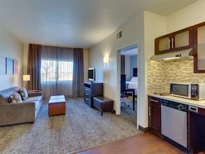 Quarto de hotel com sala de estar, cozinha compacta e quarto separado.