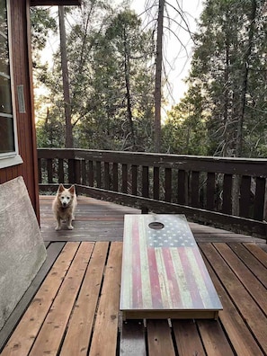 A wooden deck with a dog and a table featuring an American flag design. - Daisy’s Place | Cozy Twain Harte Cabin w/ Twain Harte Lake Access (Twain Harte)