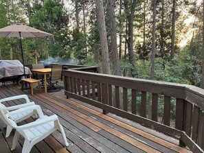 Eine Holzterrasse mit Geländer, Gartenmöbeln und einem Grill.