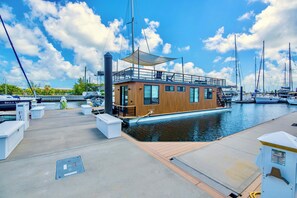 Un bateau moderne avec une coque en bois, un pont couvert et une vue sur le port de plaisance.
