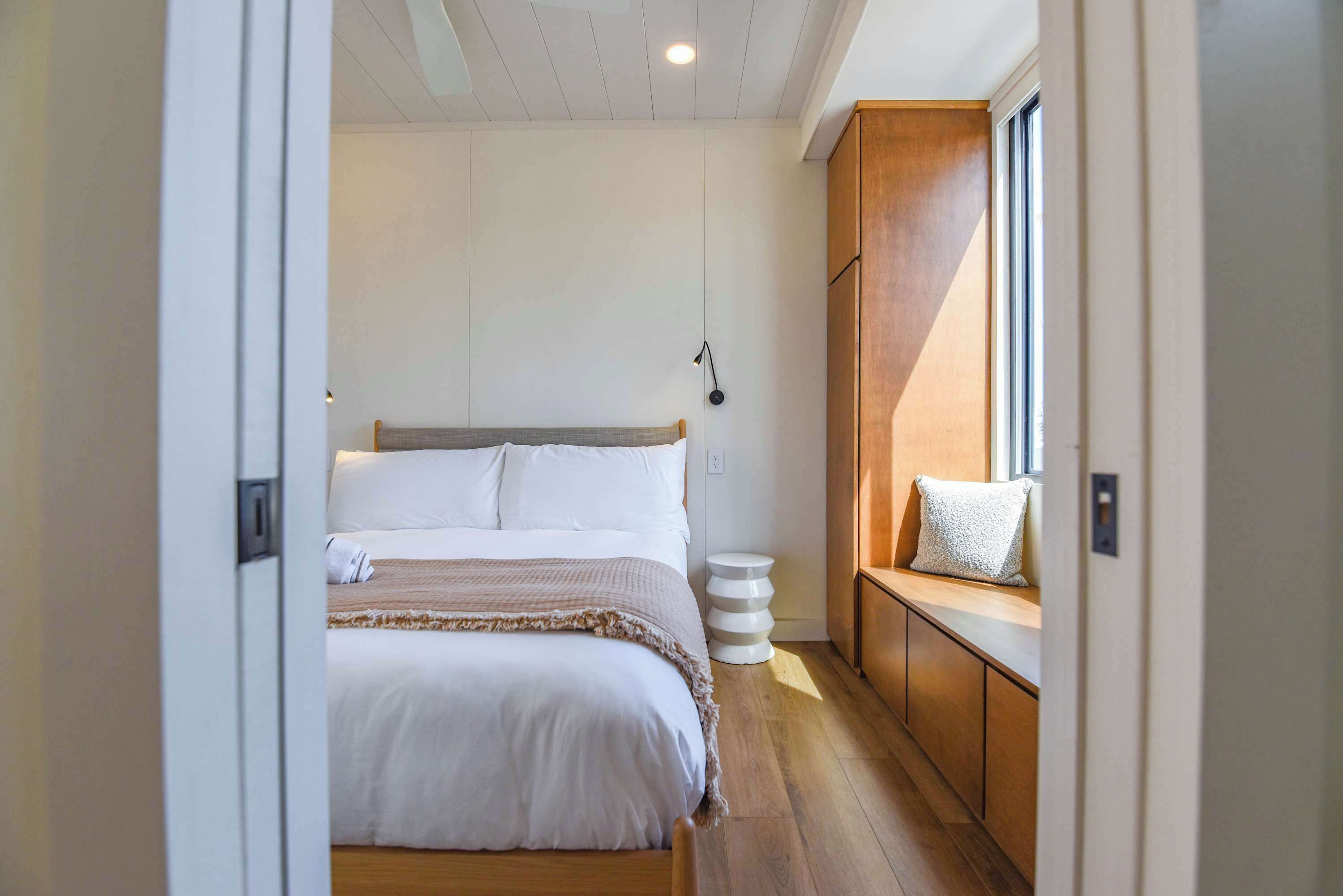 A bedroom with a bed, bedside table, lamp, and a window with a view.