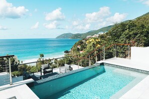 A swimming pool with a view of the ocean and a hillside.