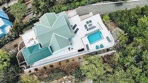 Ein Luftbild eines Hauses mit Schwimmbad, mehreren Zimmern und einem Garten.