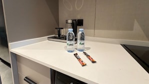 En køkkenbordplade med to vandflasker, en kaffemaskine og to chokoladebarer.