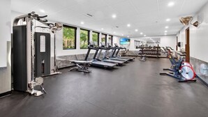 Un gimnasio con cintas de correr, máquinas de pesas y una bicicleta estática roja.