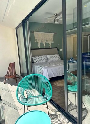 A bedroom with a bed, a hanging decor, and a view through a glass door. - Sensai Downtown by Riviera Maya Suites  (Playa del Carmen)