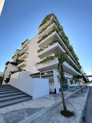 A multi-story hotel with a white facade, outdoor stairs, and a covered entrance. - Sensai Downtown by Riviera Maya Suites  (Playa del Carmen)