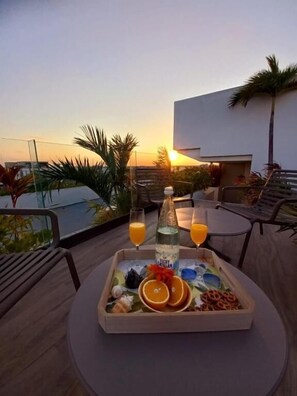 Ein Tablett mit Speisen und Getränken auf einem Tisch mit Blick auf den Sonnenuntergang.