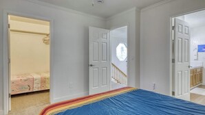 Ein Schlafzimmer mit einem Bett, einem offenen Kleiderschrank und einer Tür zu einem Badezimmer.
