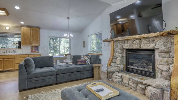 Ein modernes Wohnzimmer mit Kamin aus Stein, einem grauen Sofa und einem Fernseher über dem Kamin.