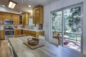 A modern kitchen with wooden cabinets, stainless steel appliances, and a dining area with a table and chairs. - Peaceful Tahoe escape next to protected forest land, minutes from beaches, trails, and adventure (South Lake Tahoe)