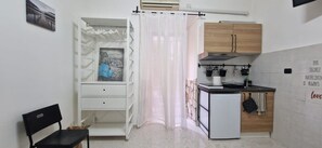 A compact kitchen with a refrigerator, wooden cabinets, a small countertop, and a window with a curtain. - Tranquility and comfort near Trastevere (Roma)