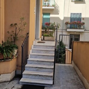A narrow stairway leading to a building entrance, with potted plants on the sides and a metal railing. - Tranquility and comfort near Trastevere (Roma)