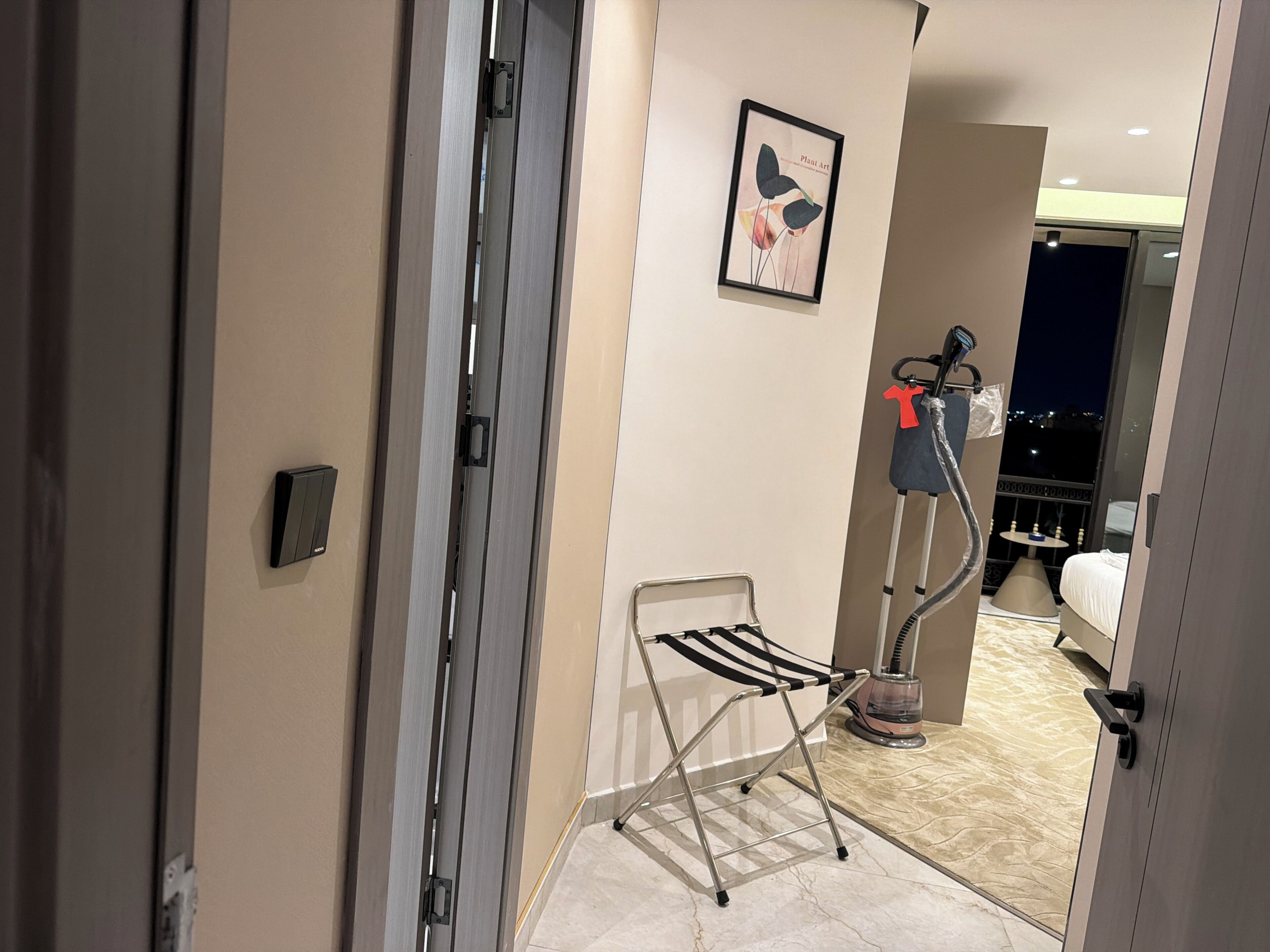 A hotel room with a bed, a standing fan, a hairdryer, and a towel rack.
