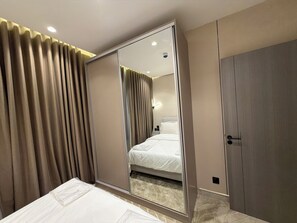Hotellihuone, jossa on sänky, vaatekaappi ja peili, joka heijastaa huonetta.