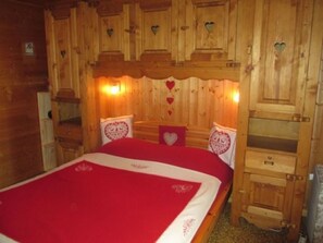 Une chambre à coucher de style cabane en bois, comprenant un lit, deux tables de chevet et une commode.