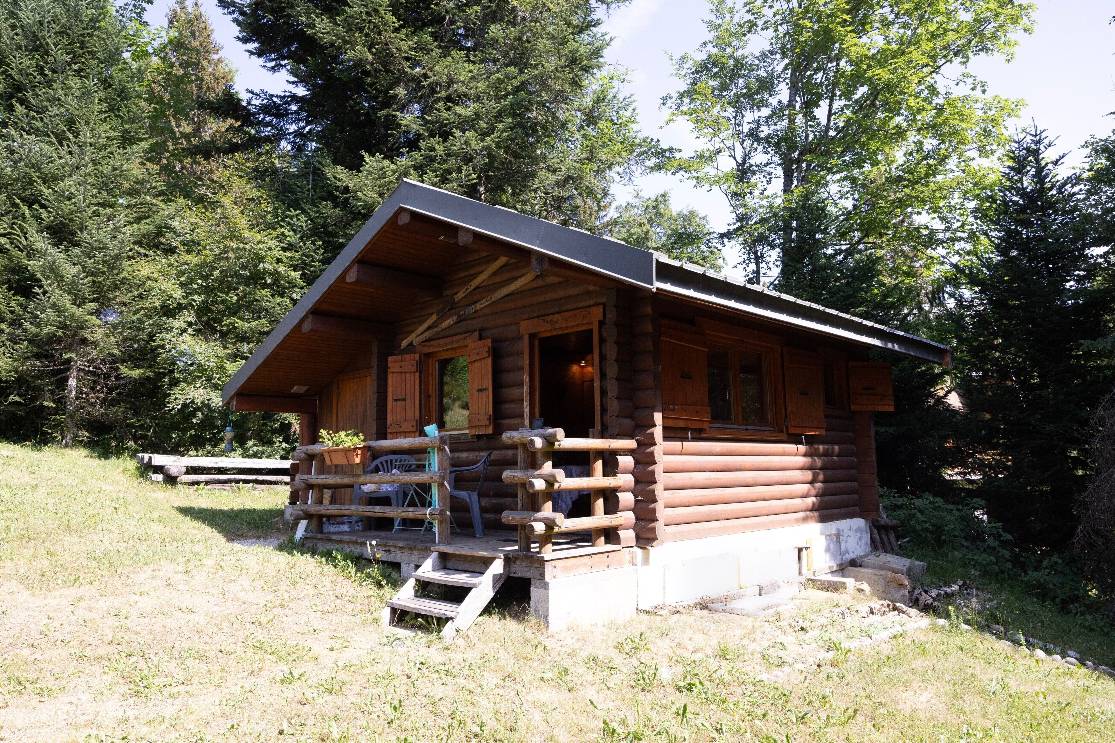 Een vakantiehuisje van hout met een veranda, trappen en een tafeltje.