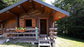 A log cabin with a wooden deck, a covered porch, and a front door.